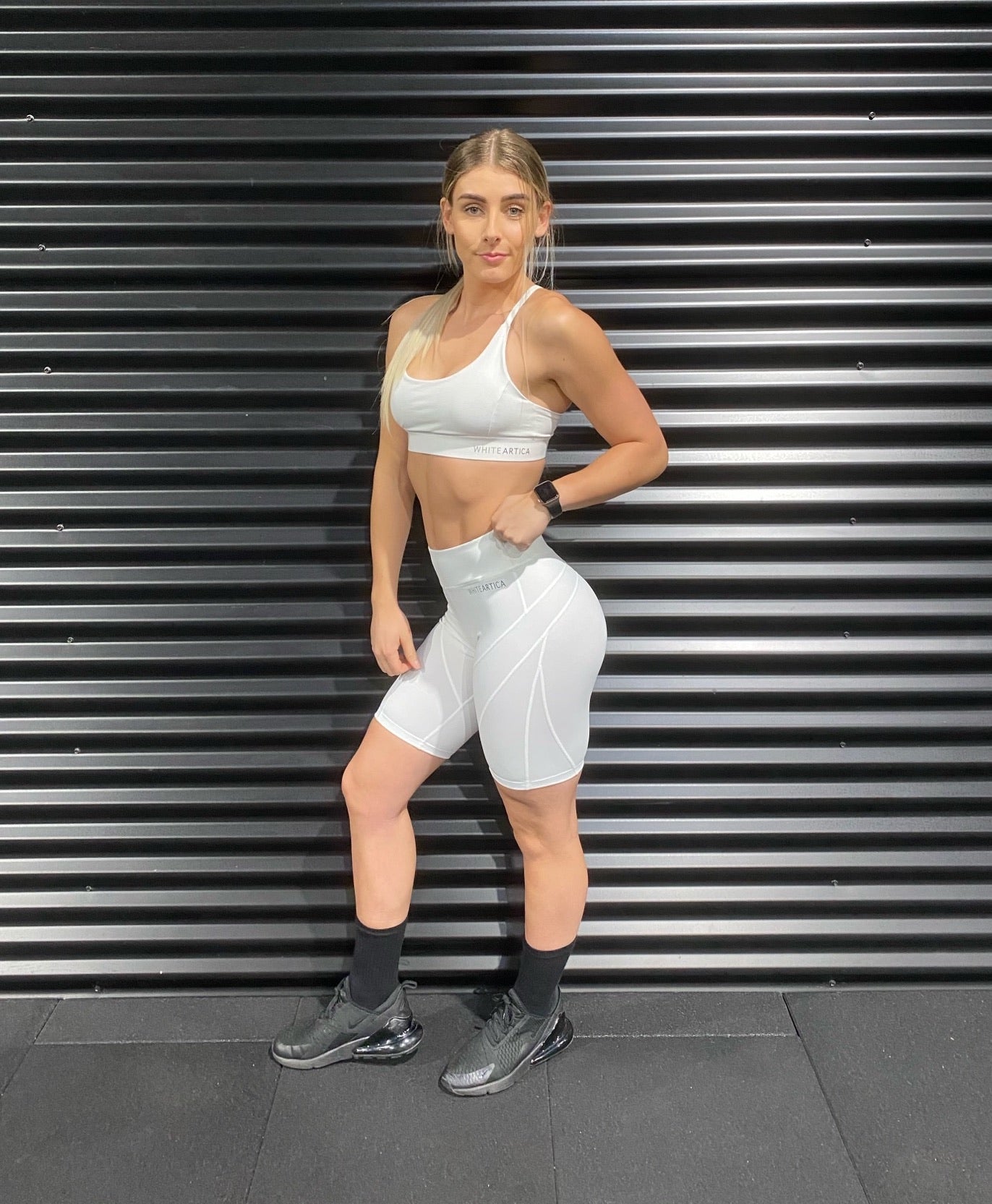 Fitness model wearing white sports bra and cycling shorts activewear at the gym